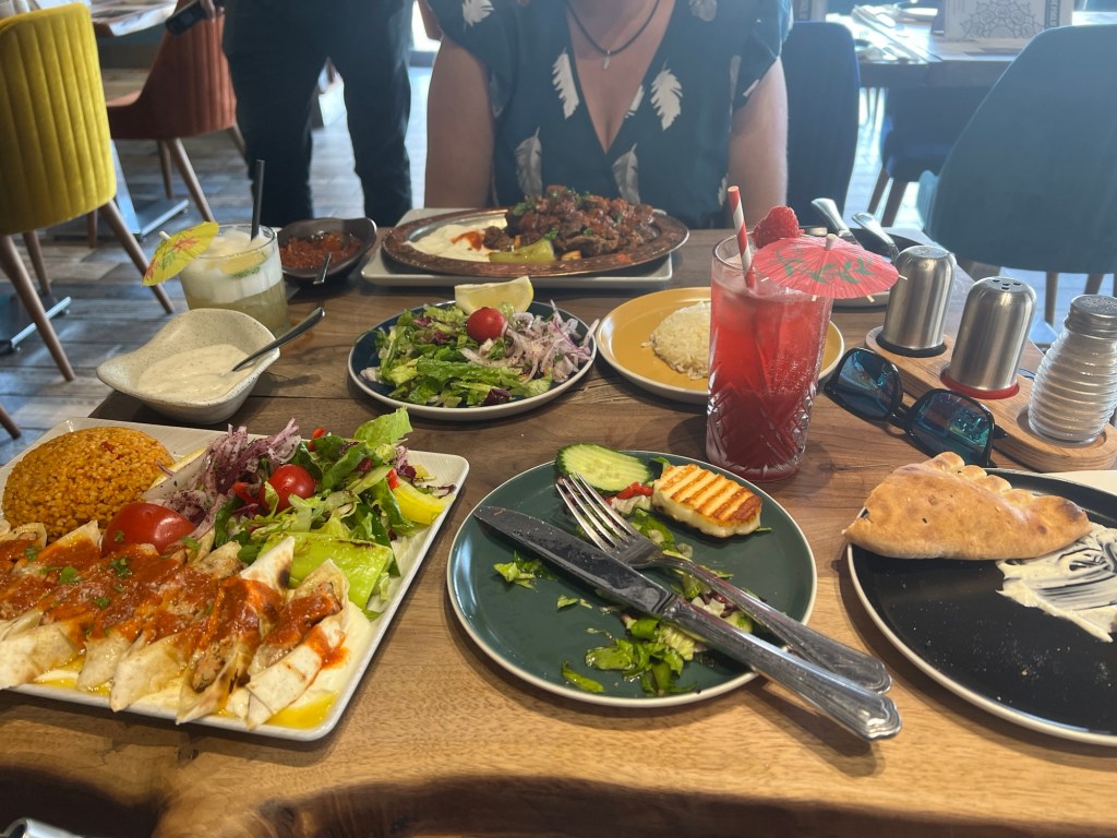 The table is covered with plates of Turkish food and yellow cocktail and a red mocktail all of which was delicious.